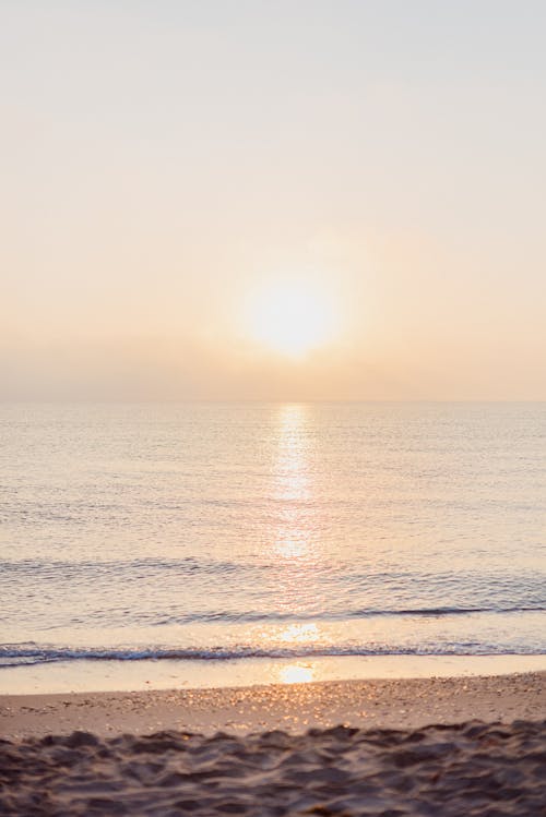 Sun setting over waving sea with sandy shore