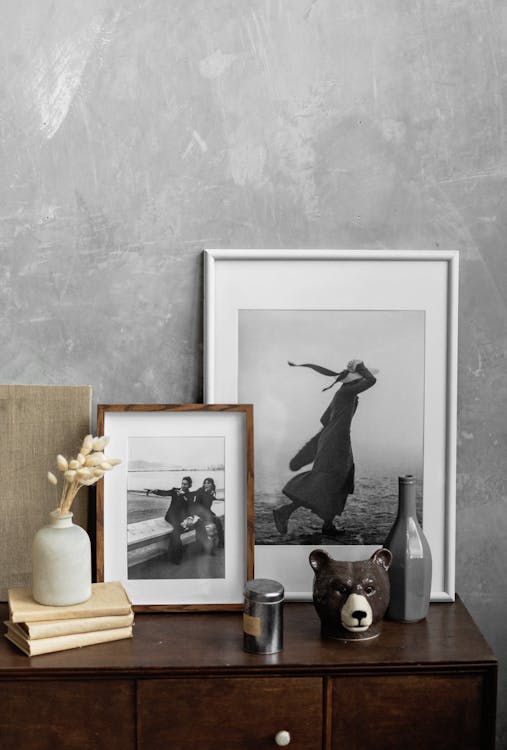 Modern home interior with a collection of framed black and white photographs and decorative objects on a wooden dresser