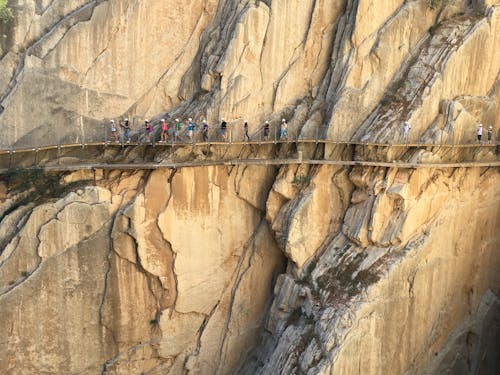 People Walking on Suspended Bridge on Cliff Edge