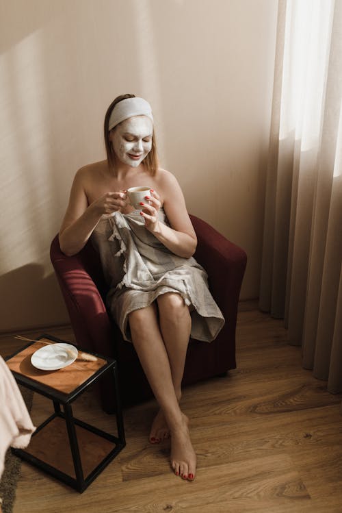 Free A Woman Wearing a Facial Mask While Holding a Cup Stock Photo