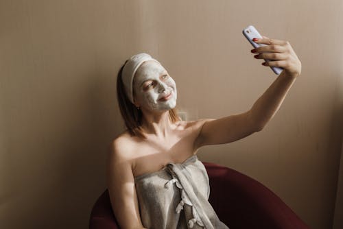 A Woman Wearing a Facial Mask and Taking a Selfie