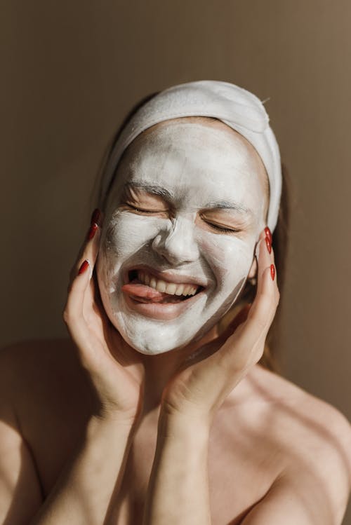 Woman With White Facial Cream with Tongue Out