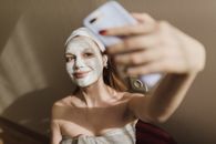 A Woman With a Mud Mask Taking a Selfie