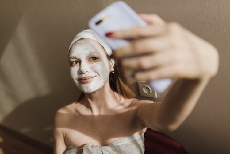 A Woman With A Mud Mask Taking A Selfie 