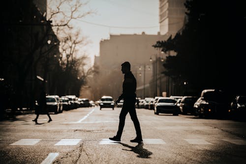 A Silhouette of a Man Crossing a Street
