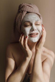 Woman enjoying a soothing facial mask treatment with a towel wrapped around her head.