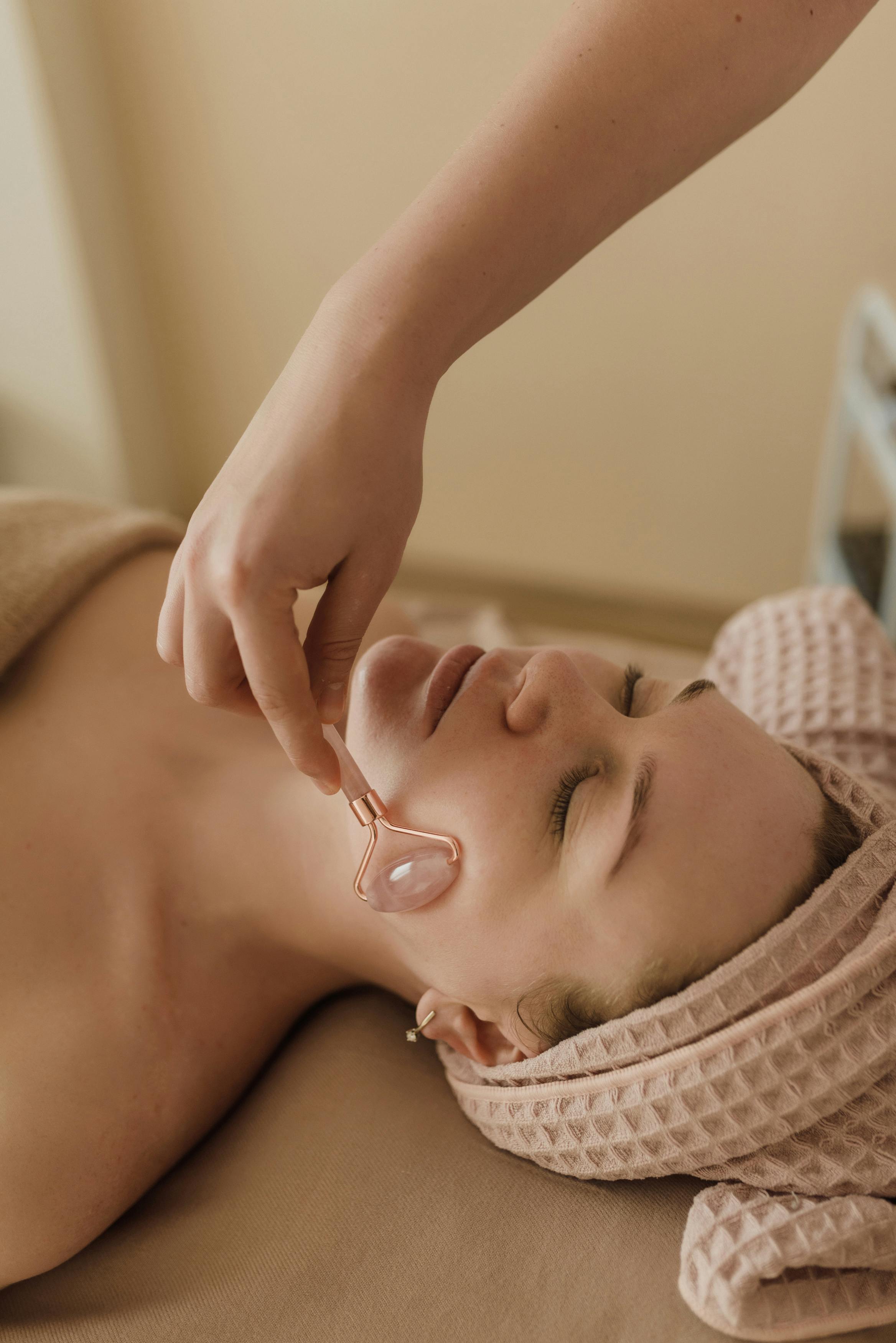 a person using a face roller on a woman