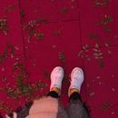 From above of crop anonymous female in casual wear and warm scarf on vivid tiled floor with fallen twigs