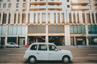 A classic white taxi parked on a city street in front of a modern building in Baku, Azerbaijan.