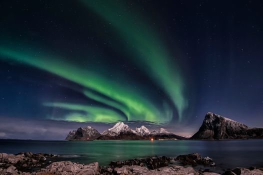 A breathtaking view of the Northern Lights over Sandnes, Norway's rugged mountains.