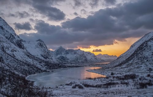 Free A dramatic winter sunset over snow-covered mountains and a frozen lake in Vareid, Norway. Stock Photo