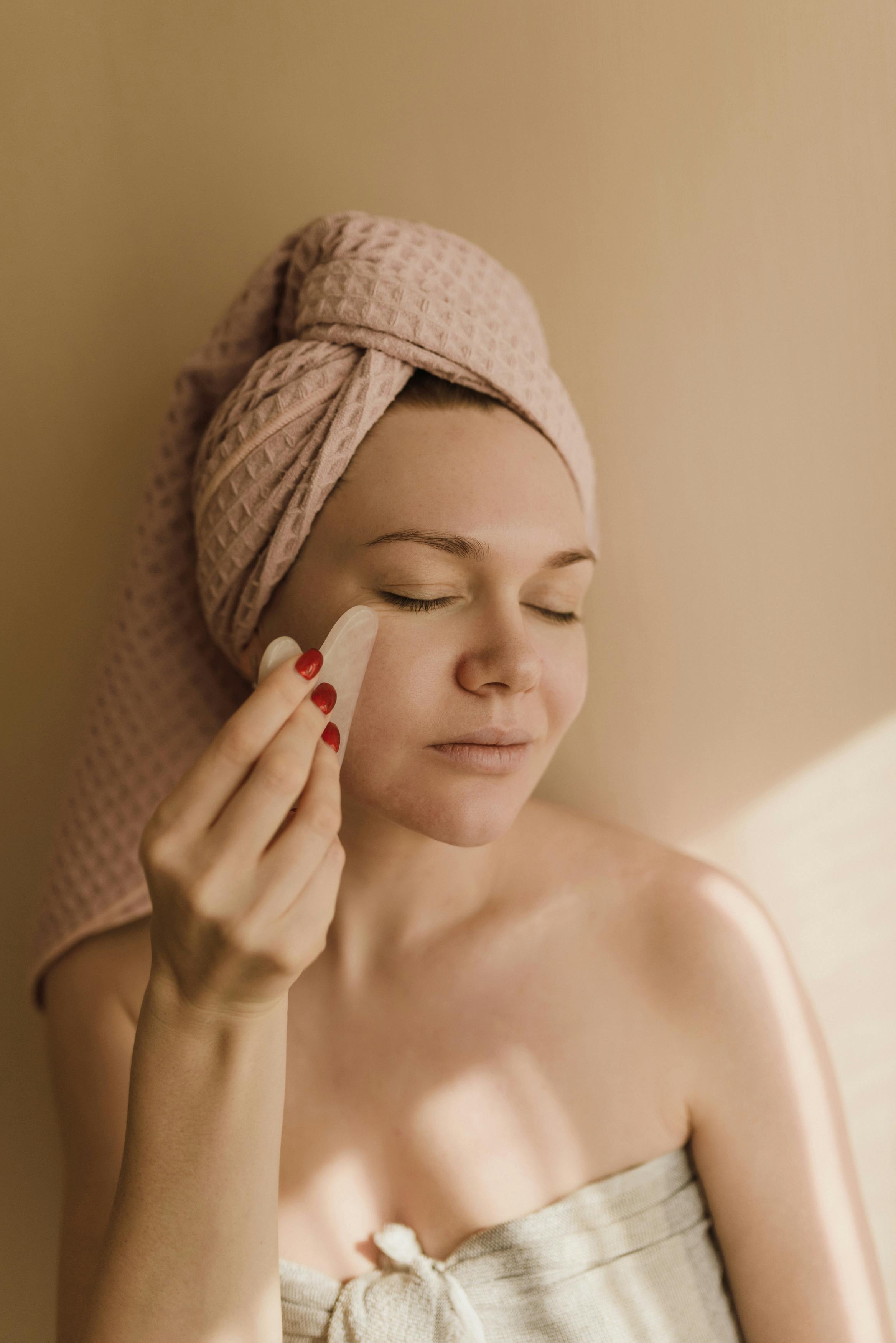 a woman using a gua sha facial stone
