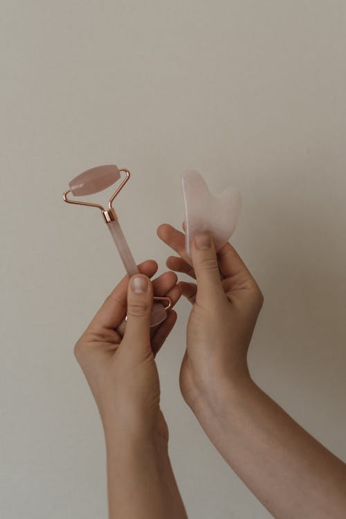 Free 
A Close-Up Shot of a Person Holding a Gua Sha and a Face Roller Stock Photo