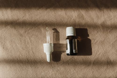 Free A brown bottle with a dropper on textured cloth captured in warm natural light, perfect for skin care context. Stock Photo