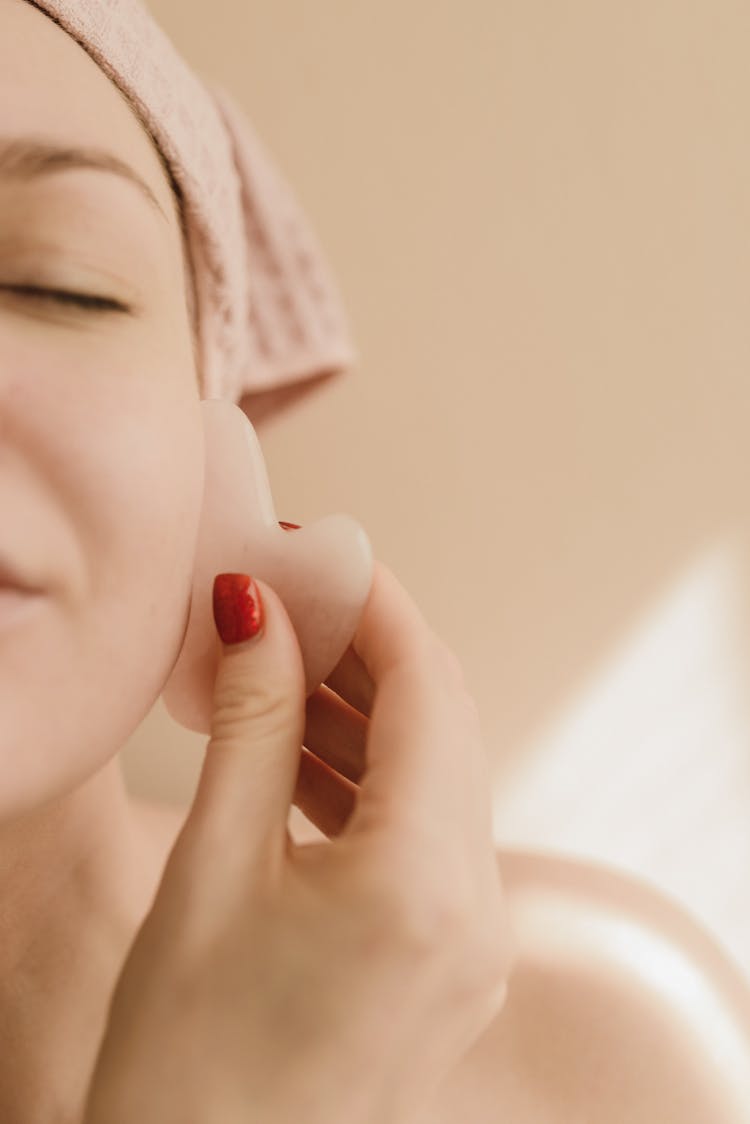 A Woman Using A Gua Sha Facial Stone