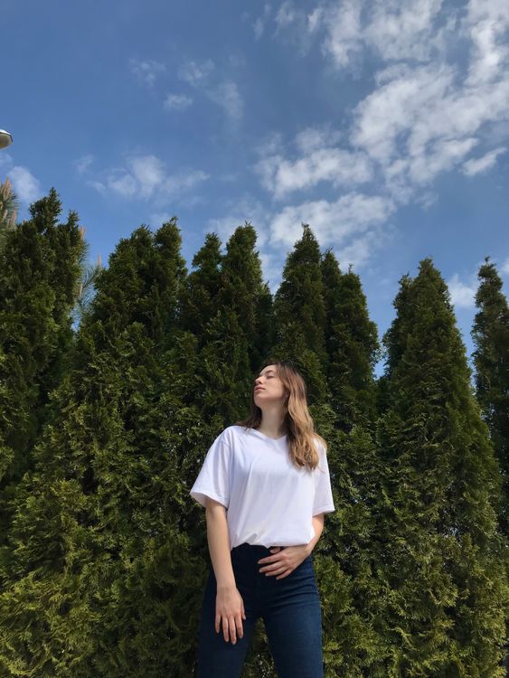 A Woman in White Shirt Standing Near Green Trees · Free Stock Photo
