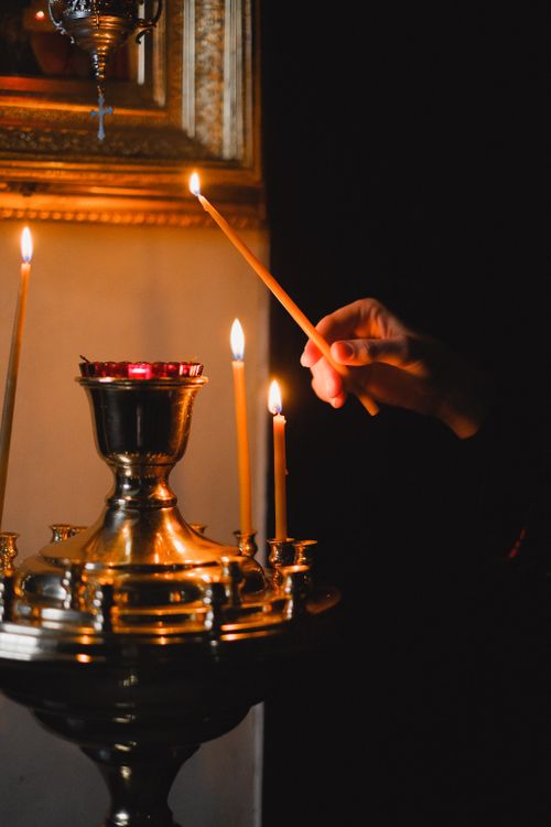 Free Hand lighting candles in a dark room creates a warm and serene ambiance. Stock Photo