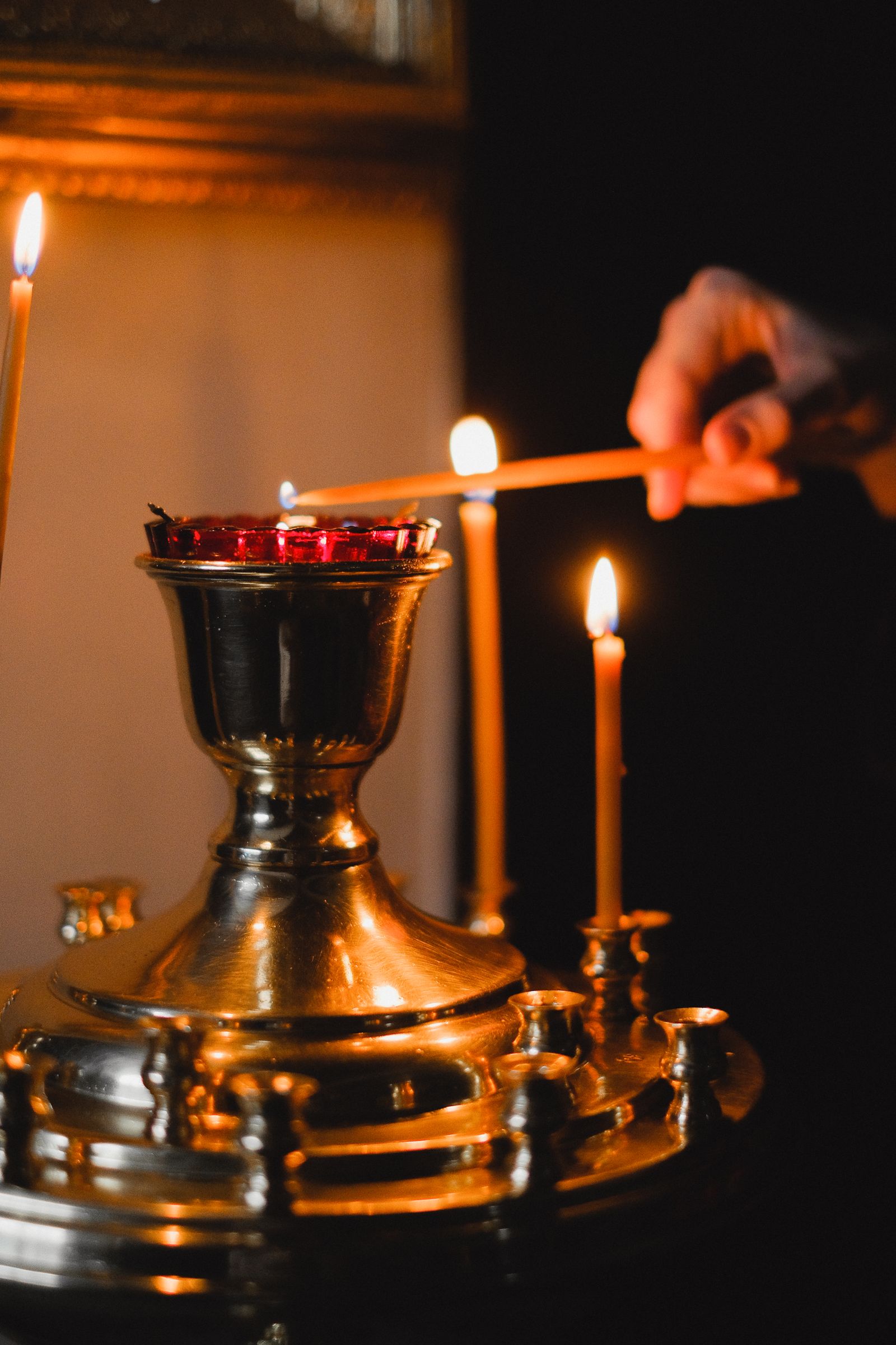 Hand lighting a candle with a warm flame