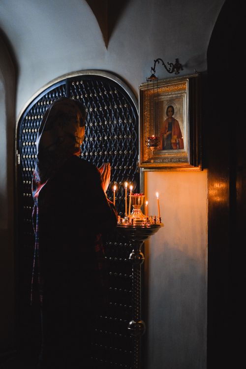 Free A woman in headscarf praying by candlelight before an icon in an Orthodox church. Stock Photo
