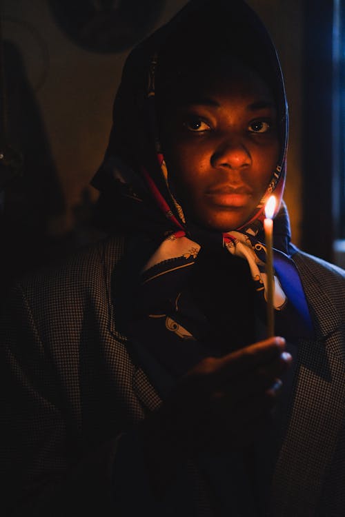 A Woman Holding a Lighted Candle Looking at Camera