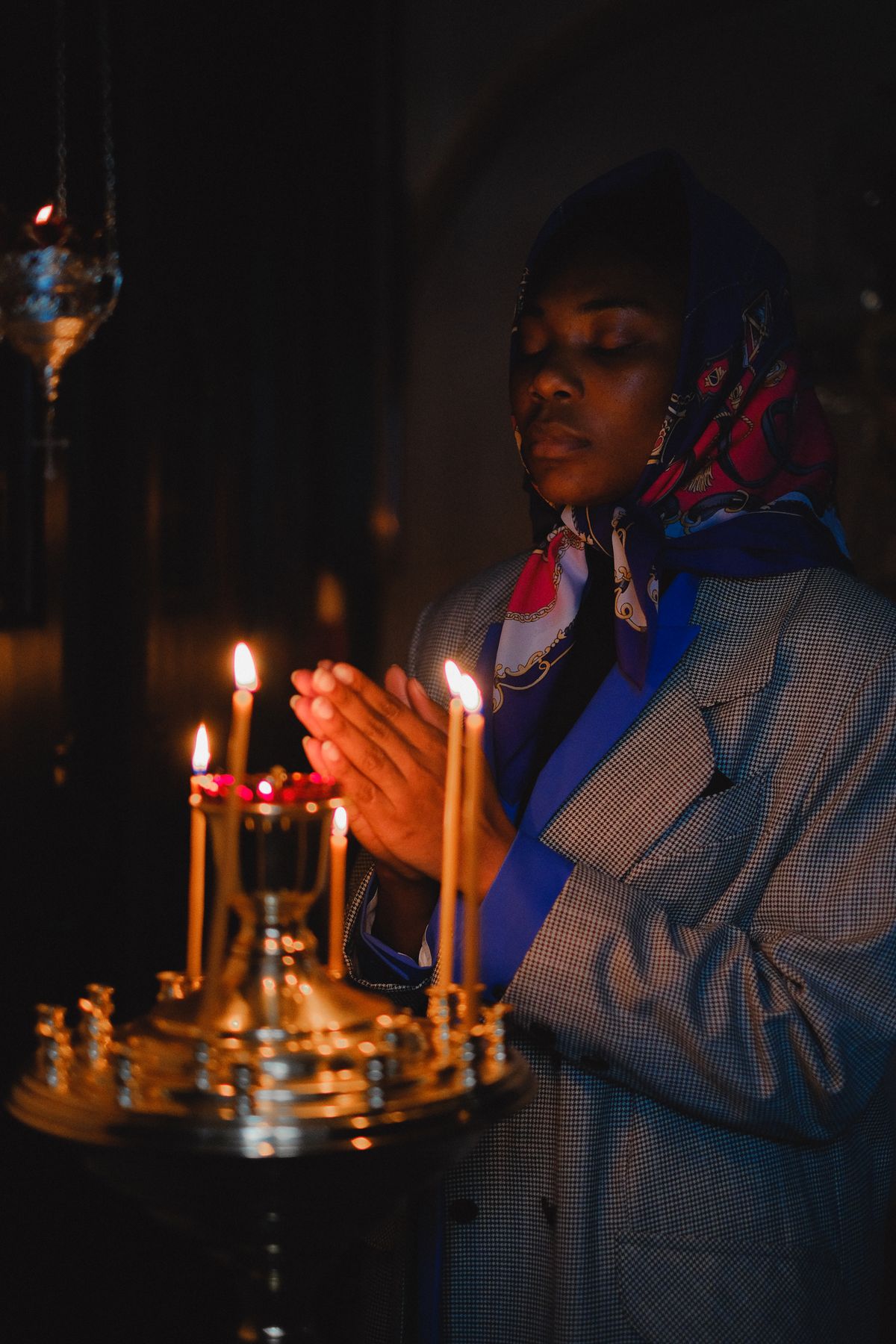 Mujer en oración frente a velas encendidas