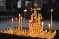Golden crucifix with lit candles in a dimly lit church, creating a spiritual ambiance.