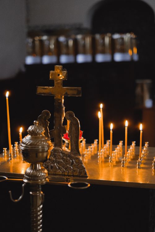 Free A serene and detailed view of lit candles and a cross in a church setting, evoking a spiritual ambiance. Stock Photo