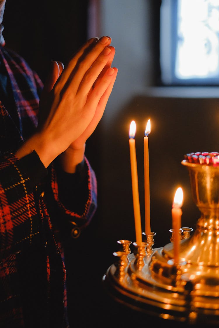 Hands In Prayer Near Candles In Church