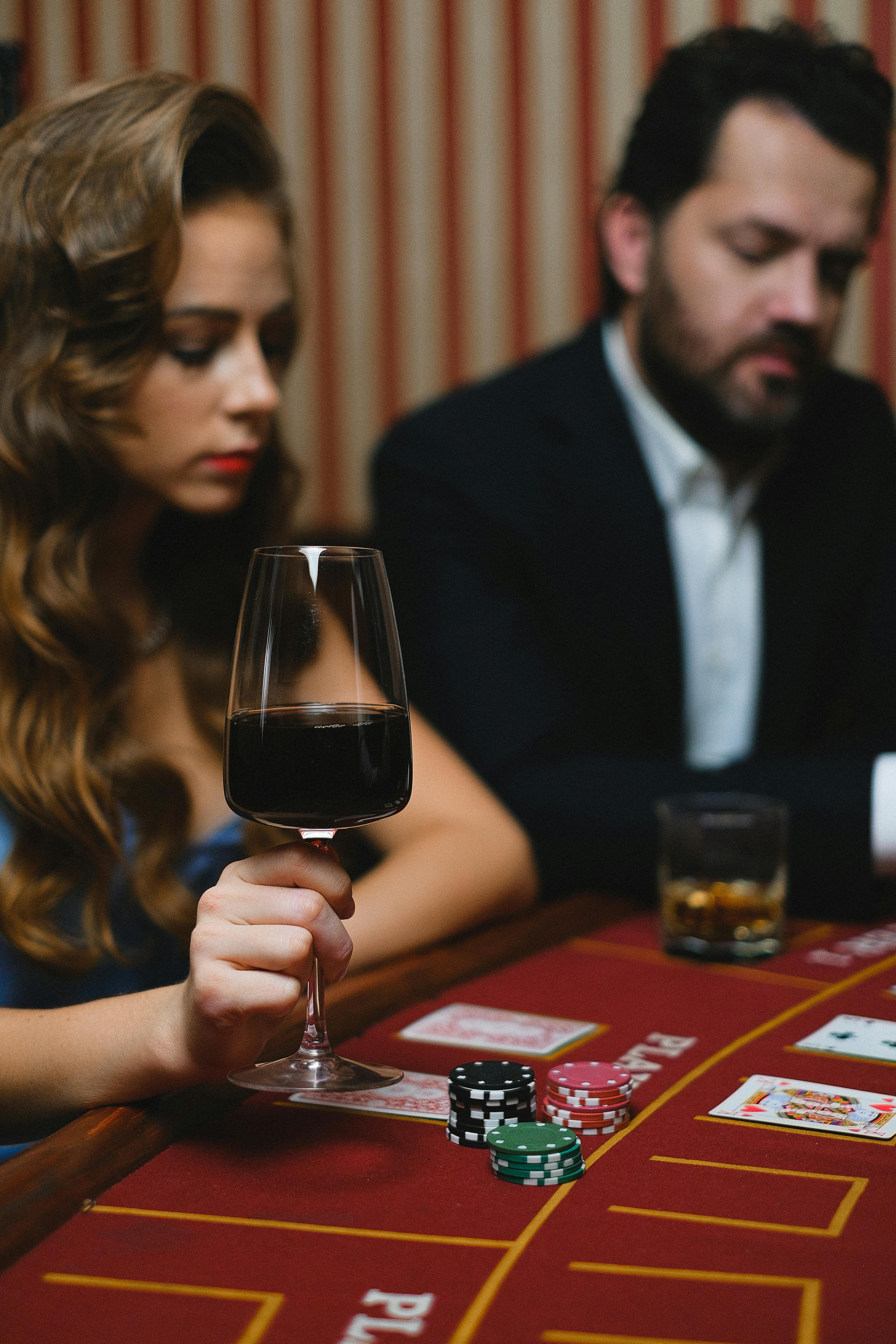 elegant man and woman playing poker in a casino and drinking wine