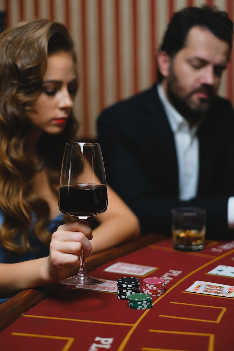 Elegant Man And Woman Playing Poker In A Casino And Drinking Wine 