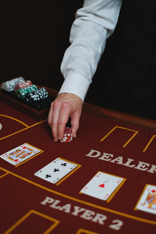 Close-up of a Man Putting Casino Tokens on a Table in a Poker Game 