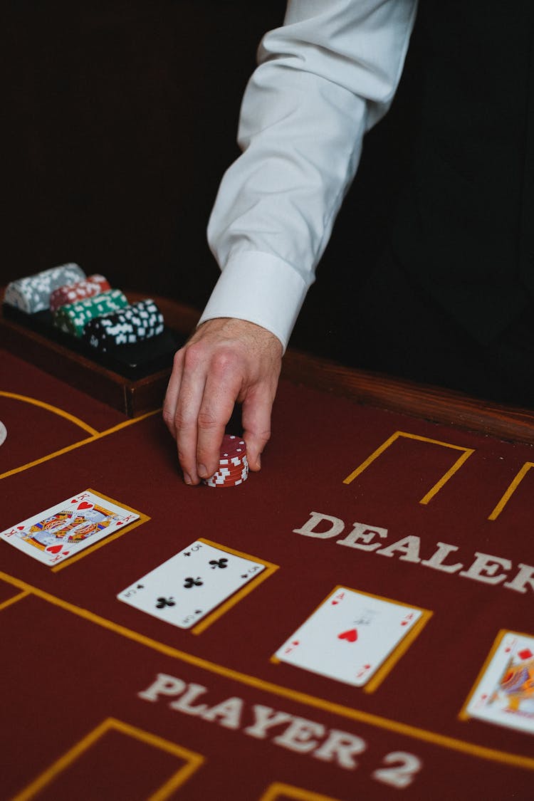 Close-up Of A Man Putting Casino Tokens On A Table In A Poker Game 