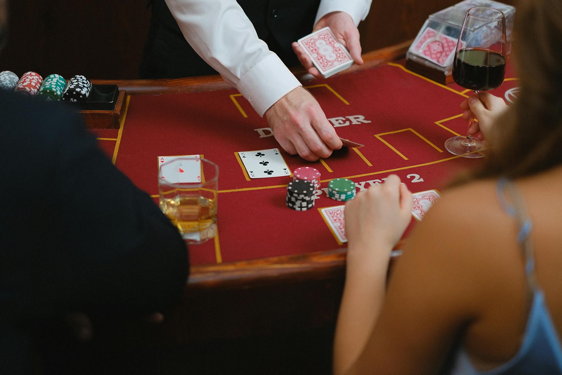 A dynamic scene at a casino card table with players engaged in a game featuring poker chips and drinks.