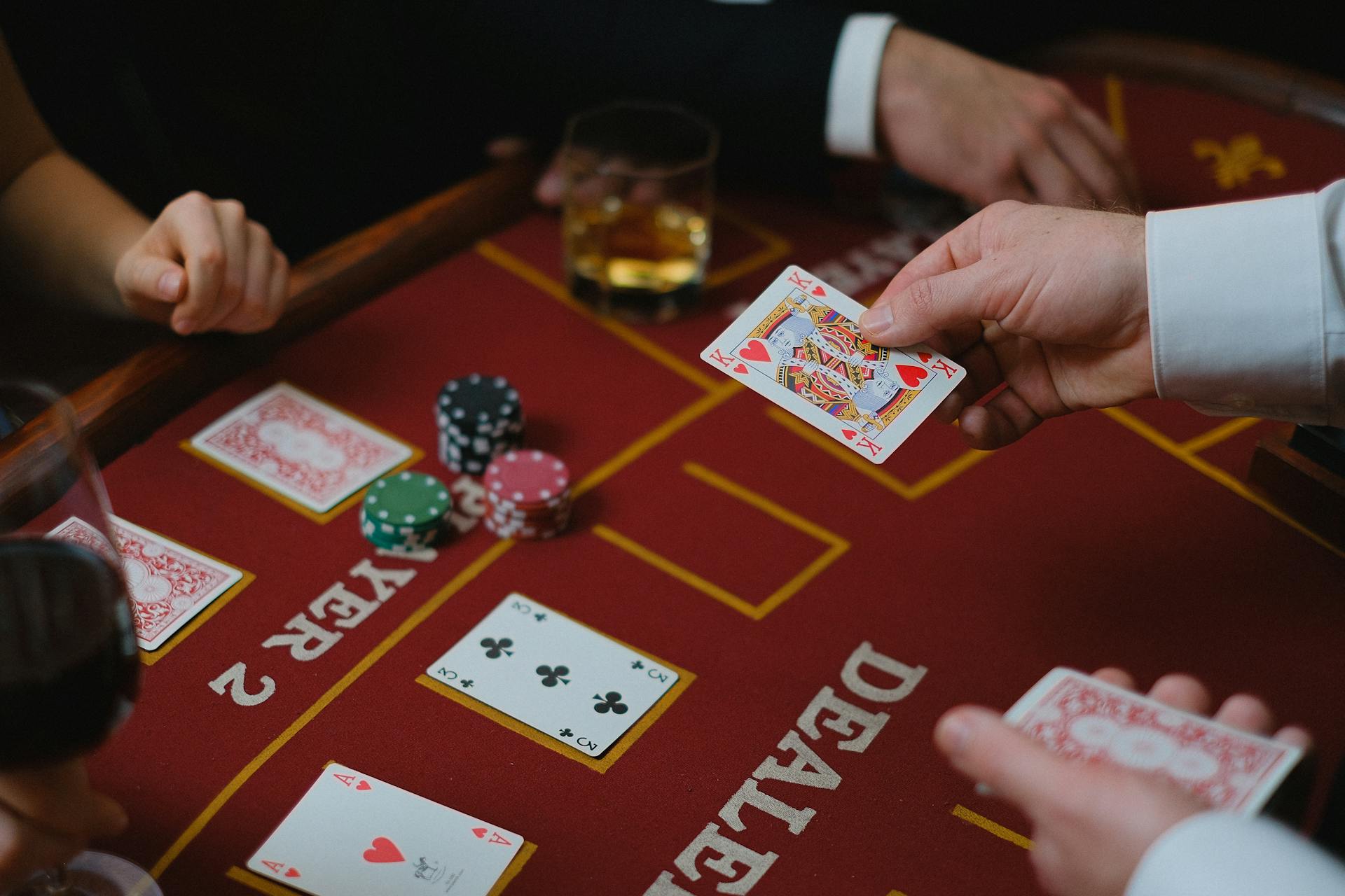 Close-up view of a casino game with cards and chips on the table, featuring player interaction.