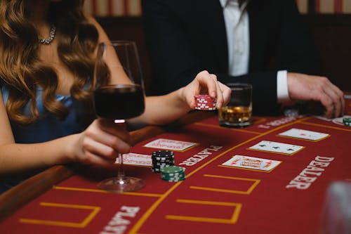 Elegant Man and Woman Playing Poker in a Casino and Drinking Wine 