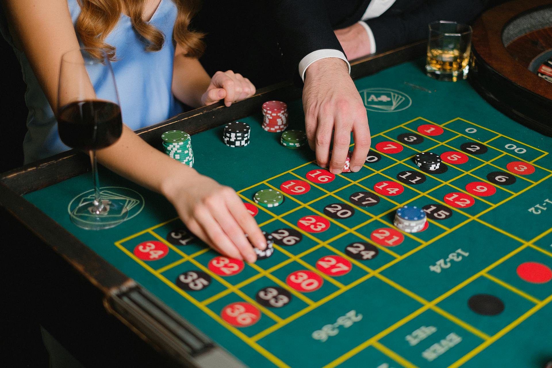 Two people playing roulette at a casino table, placing bets for a thrilling night.