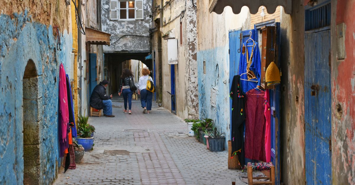 Charming alley in Essaouira with vibrant textiles and historic architecture.