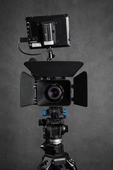 Modern professional video camera cage with lenses and monitor with wire placed against gray background in contemporary studio with contemporary equipment