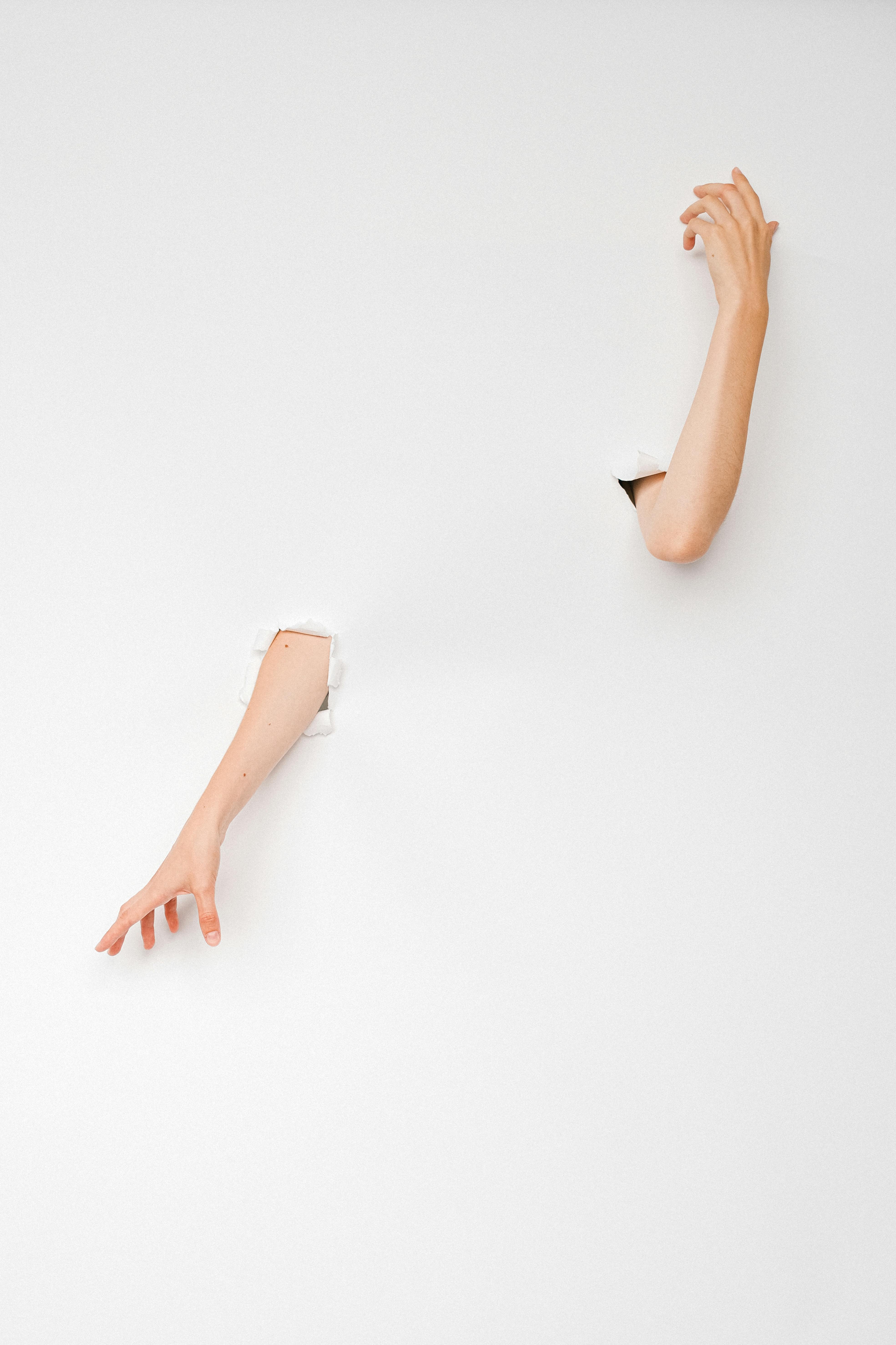 Artistic photo of two arms emerging through a white surface, representing creativity and minimalism.