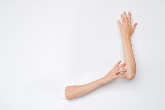 A creative and artistic image of hands extending from a hole in a white wall, highlighting human expression.