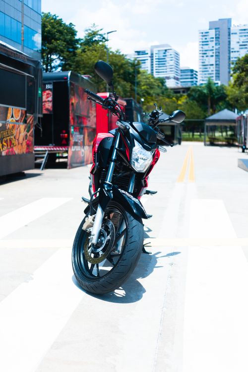 Free A modern motorcycle parked on an urban street with city buildings in the background. Stock Photo
