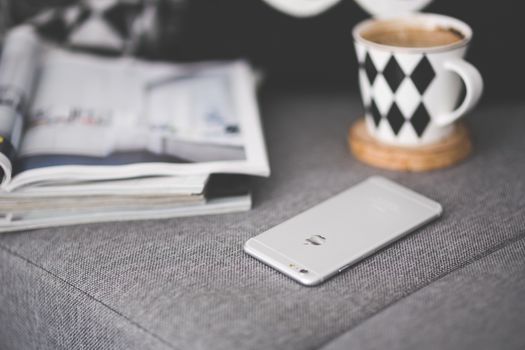 A cozy indoor setup featuring a smartphone, coffee mug, and magazine, perfect for relaxing moments.