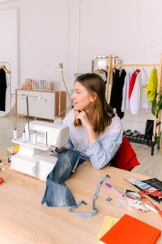 A woman using a sewing machine in a brightly lit fashion studio.