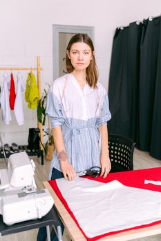 Portrait of a fashion designer in her studio, working on sewing garments with a sewing machine.
