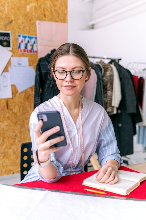 Free A Woman Wearing Eyeglasses Holding a Smartphone Stock Photo