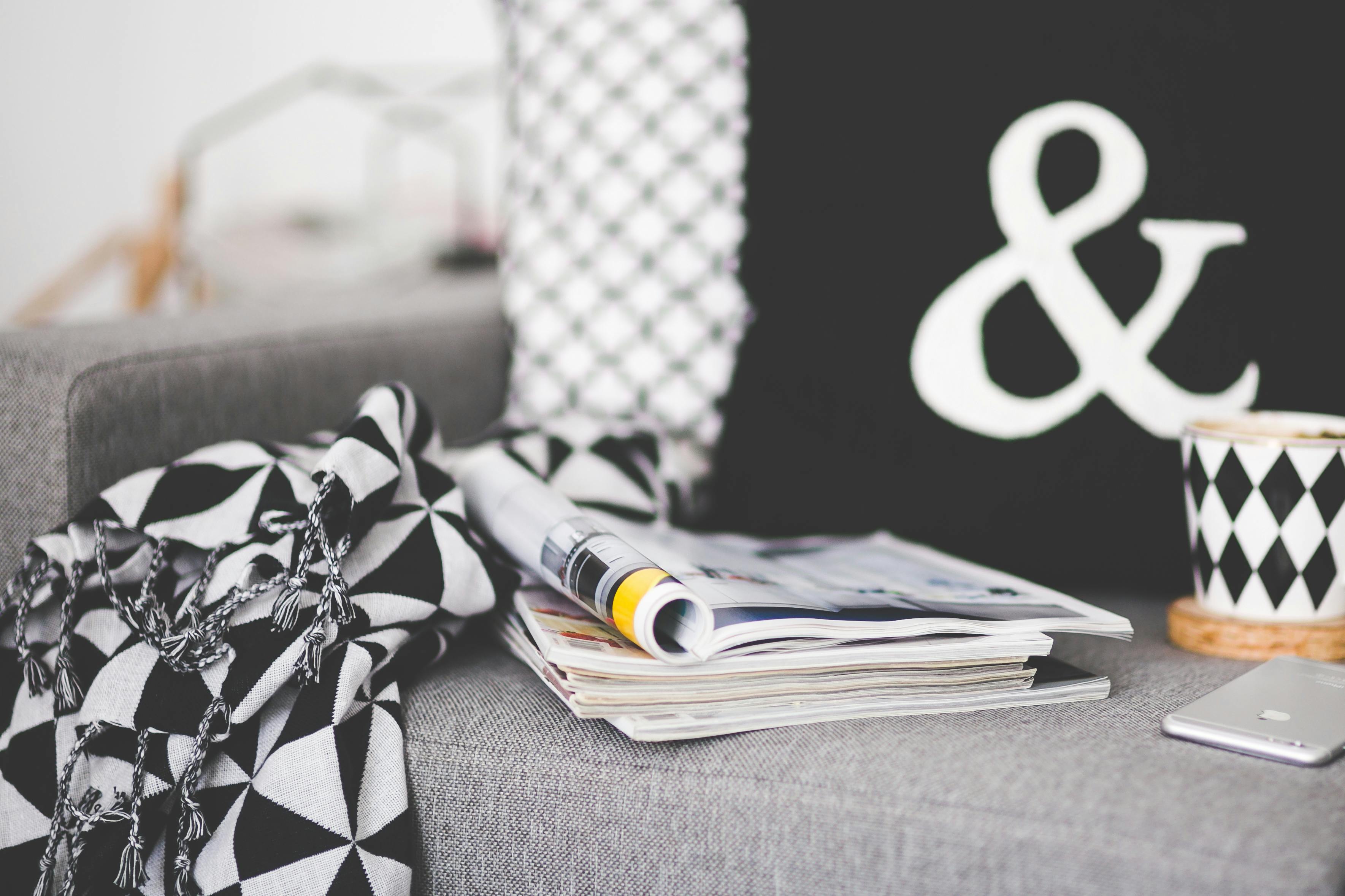 close of magazines mug and phone on a couch