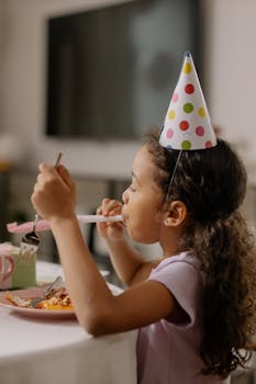 A young girl enjoying a birthday celebration with desserts and party accessories.