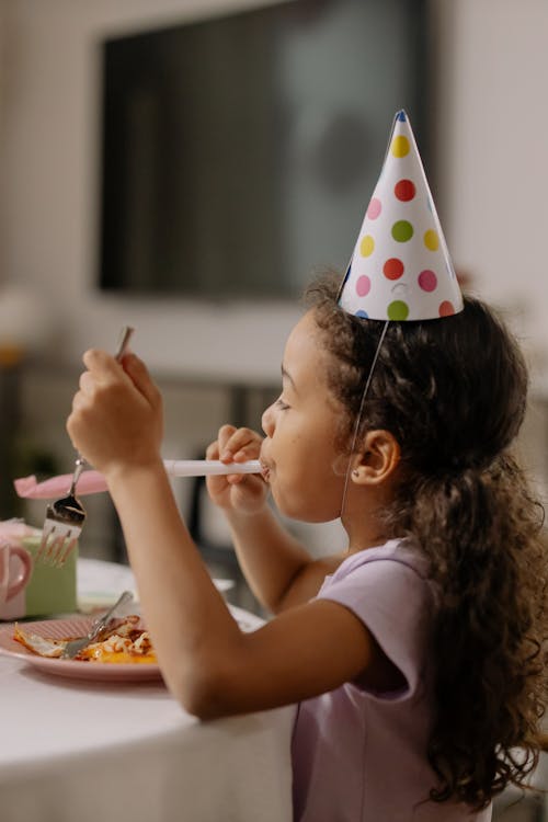 Free Girl in Purple T Shirt Blowing Party Horn Stock Photo
