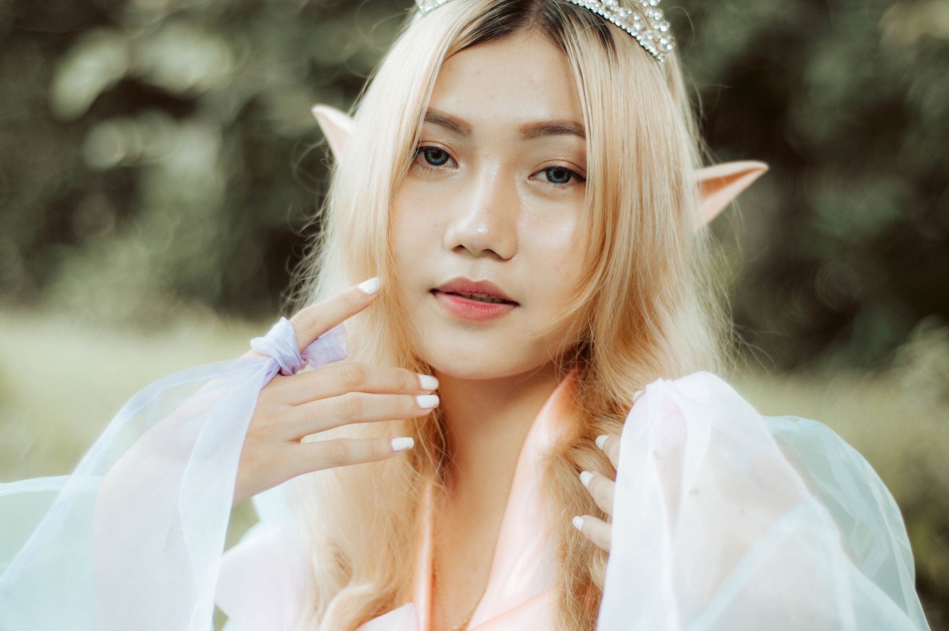 Close-up portrait of a woman in elf costume with blonde hair and pointed ears, looking at the camera.