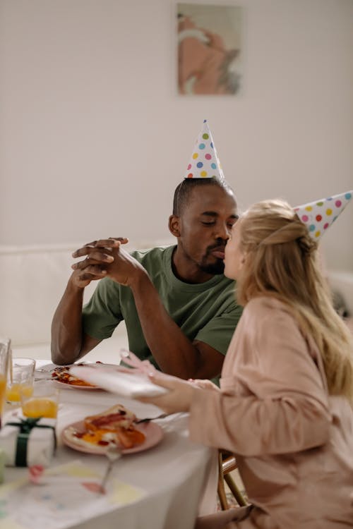 Free A Couple Wearing Party Hats while Kissing Each Other Stock Photo